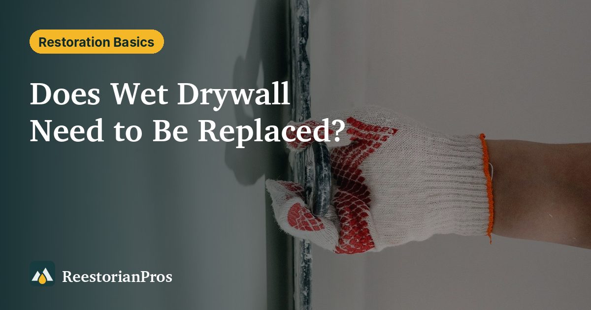 Hand in a work glove pressing a trowel against a gray wall